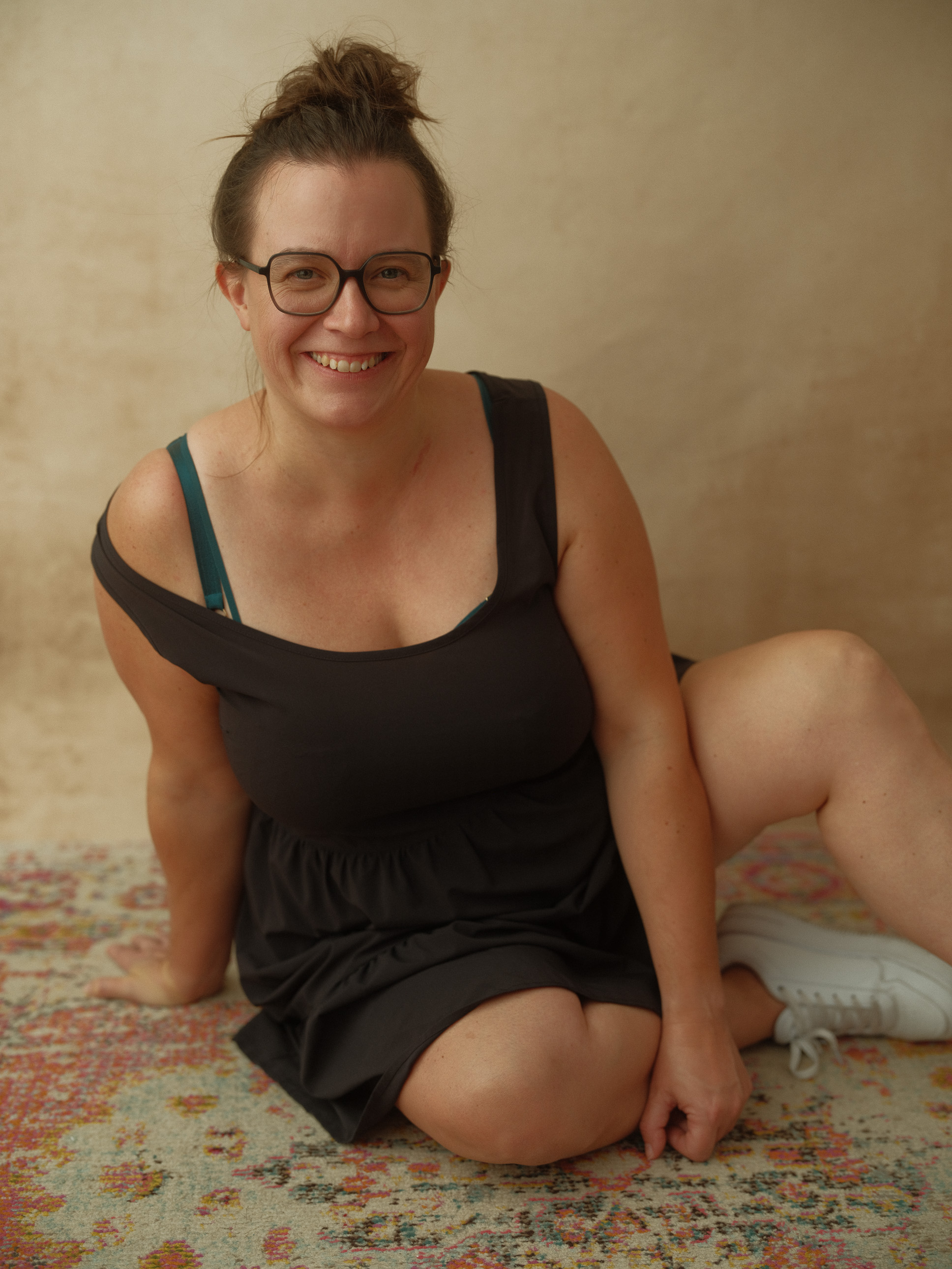 Astrid lächelnd am Boden sitzend in schwarzem luftigen Sommerkleid